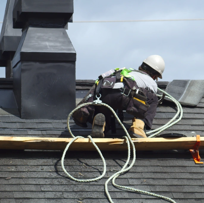 Photo of a roofer on top of a black shingle roof in Austin, Texas.